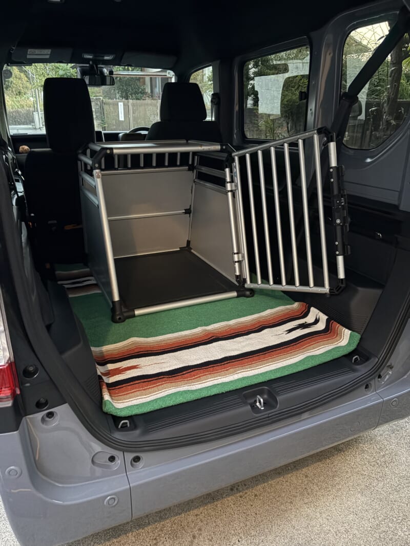 後部座席を畳み、緑のラグの上に大型犬用ケージを載せたN-VANの荷室
